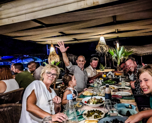 Manolis Zervakis partageant un dîner convivial avec des amis et de la famille dans un restaurant en plein air en Crète.